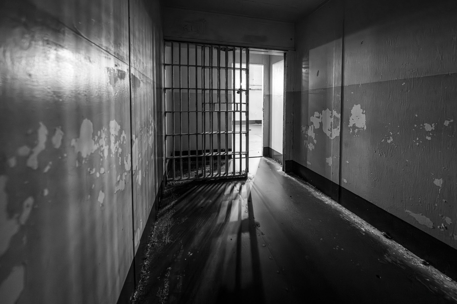 Corredor de penitenci&aacute;ria levando at&eacute; uma grade que leva a outro pavilh&atilde;o.